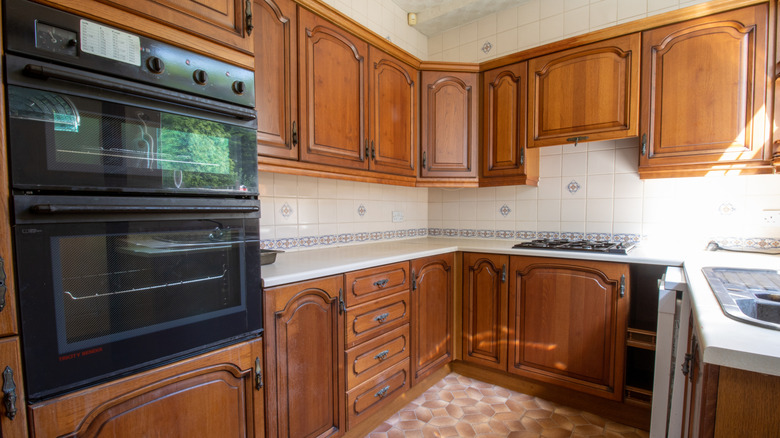Dated kitchen with dark wooden cabinets with heavy trim