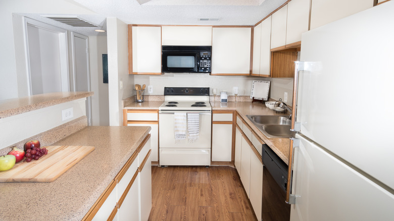 Old-fashioned kitchen with wooden floors and white laminate cabinets