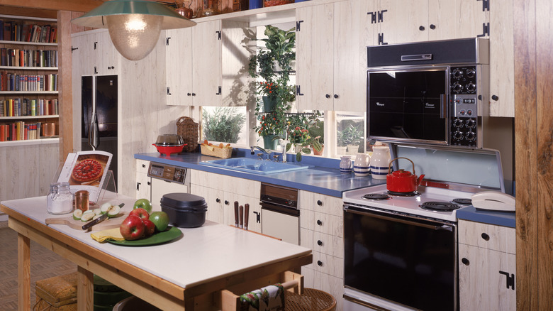 Vintage kitchen with blue countertops, white wooden cabinets, and a work table in the middle