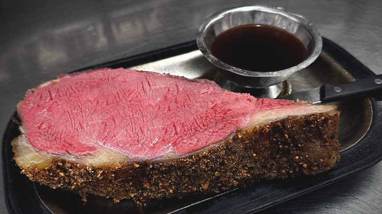 A plate of prime rib with a dipping bowl of jus