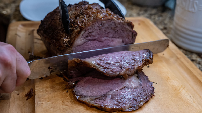 Someone slicing into a cooked prime rib roast