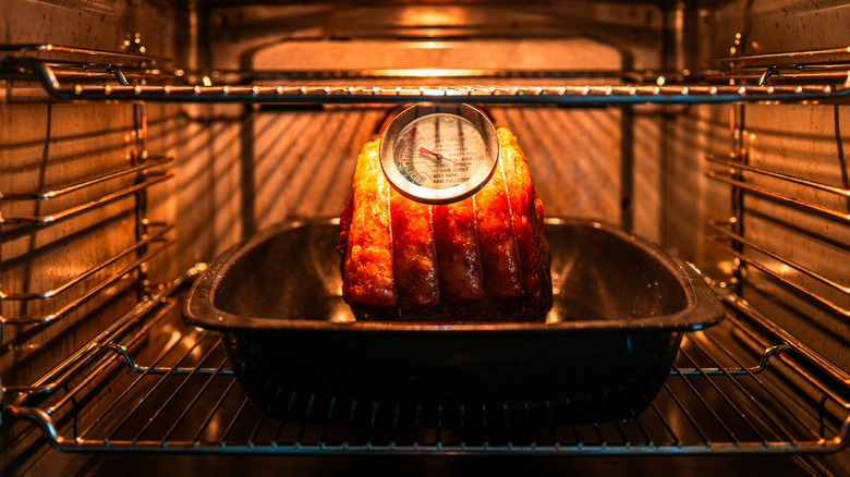 A prime rib roast cooking in an oven with a thermometer in view