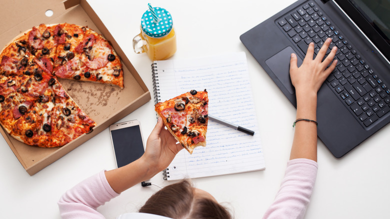 student eating pizza while studying