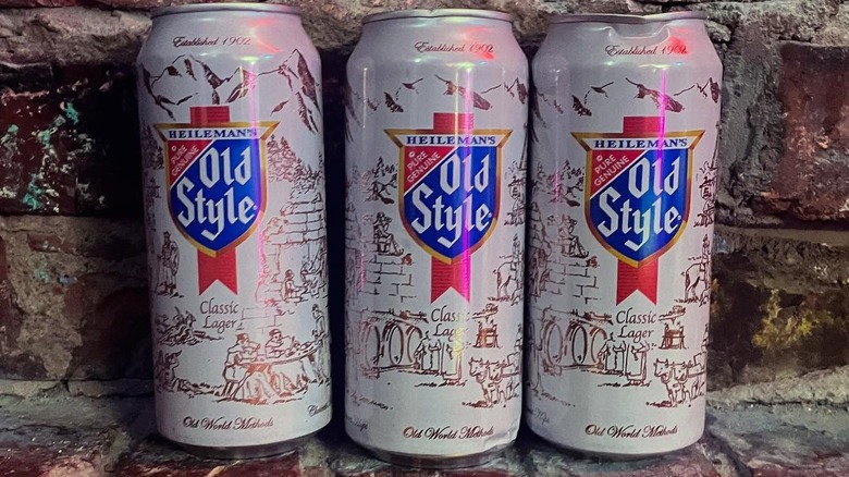 Three large cans of Old Style beer posed on a brick background