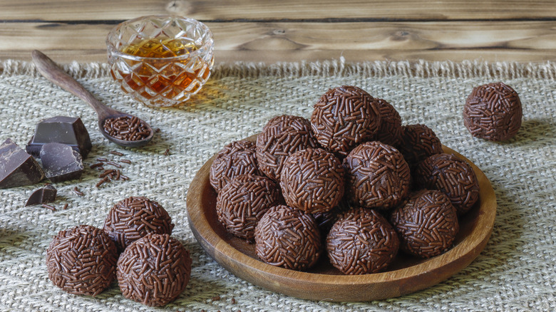 a bowl of rum balls next to a glass of rum