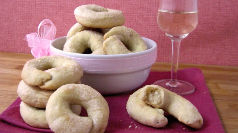 a bowl of wine cookies next to a glass of white wine