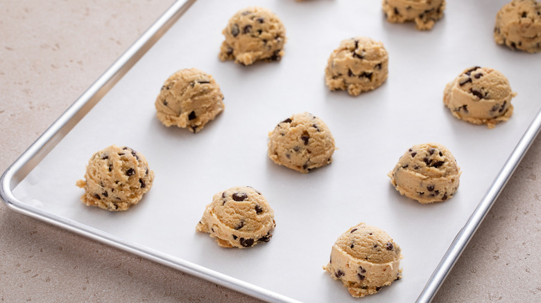 Balls of chocolate chip cookie dough on baking tray