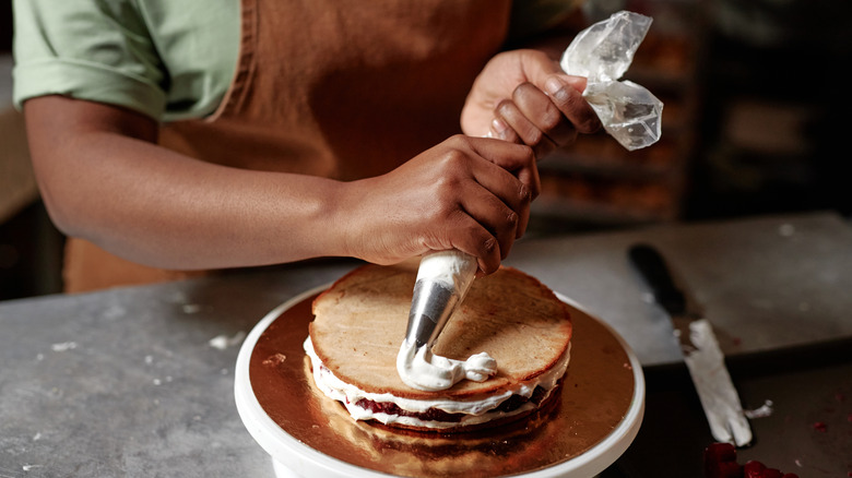 Person using half-filled piping back to ice layer cake