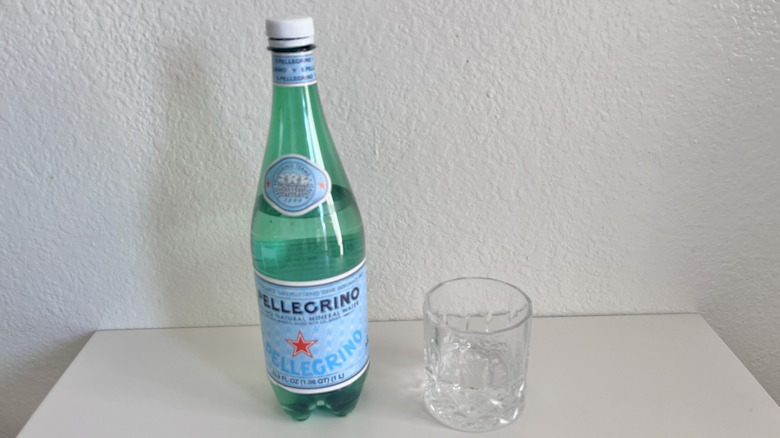 Bottle of San Pellegrino Sparkling Natural Mineral Water on a table next to a glass