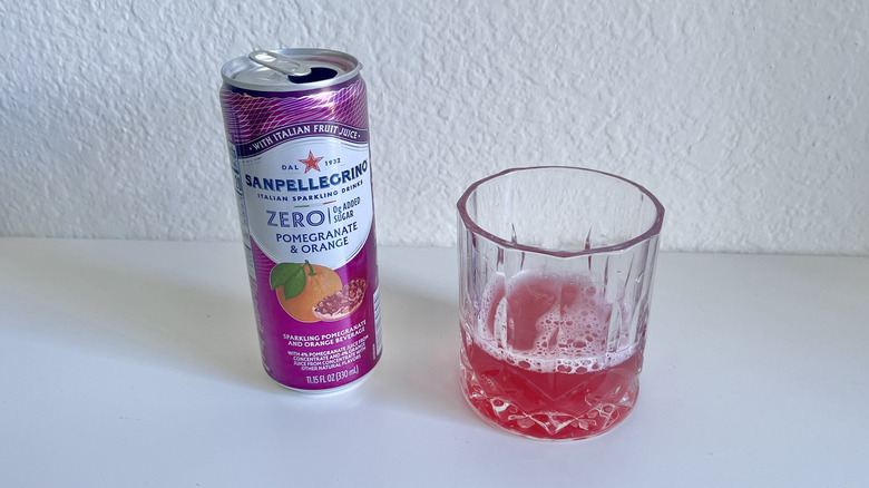 Glass with Pomegranate and Orange Zero Sugar Sparkling Drink with a can next to it