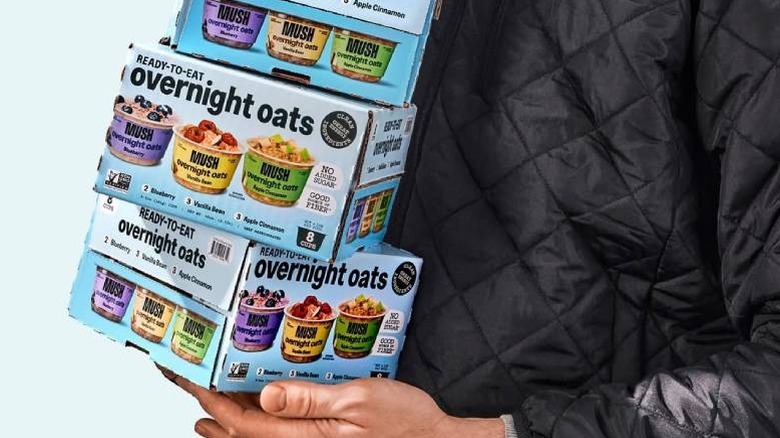Man wearing a black jacket and holding several boxes of MUSH Overnight Oats