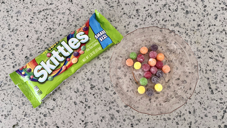 Bag of  Sour Skittles with candies on plate