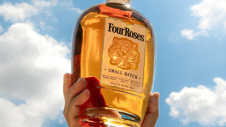 A bottle of Four Roses Small Batch held up outside with sunlight shining through it
