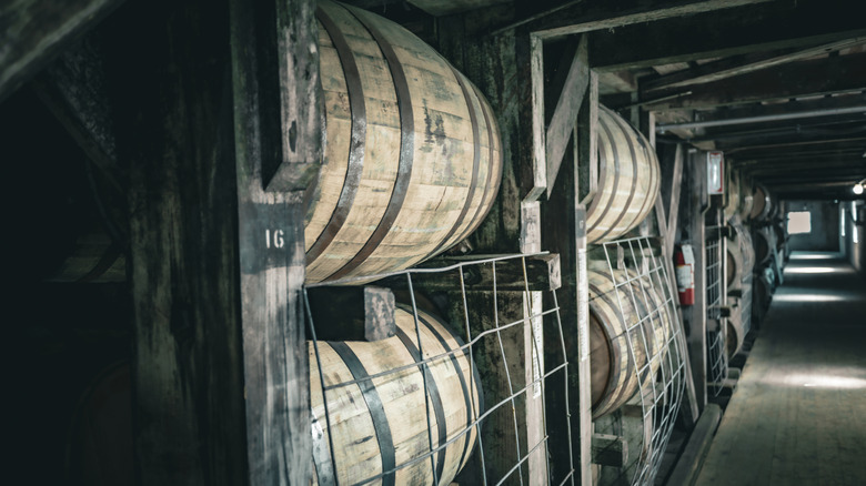 Stacks of barrels shown down a corridor in a wooden warehouse