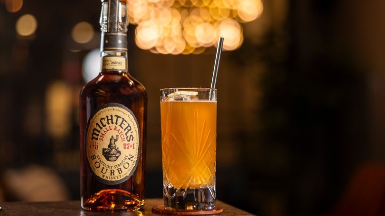 A bottle of Michter's US*1 Small Batch Bourbon placed on a table next to a cocktail