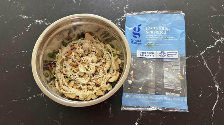 Salad in bowl next to everything seasoned salad bag