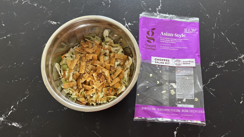 Salad in bowl next to Asian-style salad bag