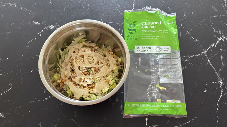 Caesar salad in bowl next to Caesar salad bag