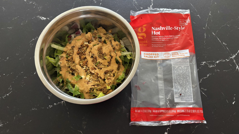 Nashville-style hot salad in bowl next to salad bag