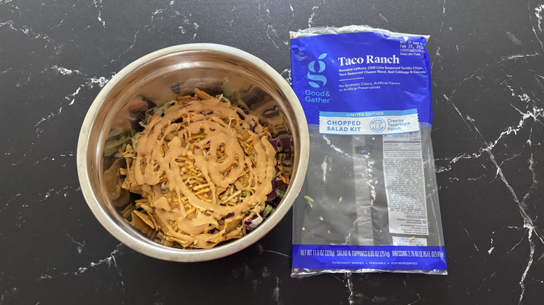 Taco salad in bowl next to salad bag