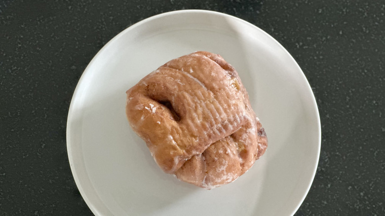 Overhead image of apple fritter donut on white plate on black countertop