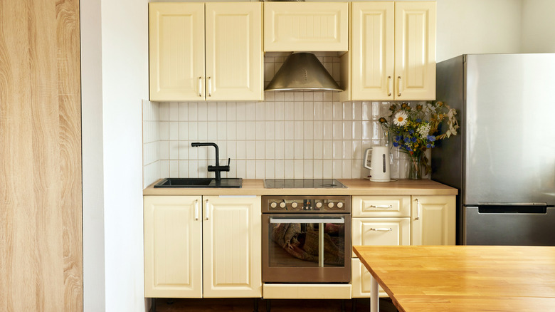 A small kitchen with butter yellow cabinets and very simple design
