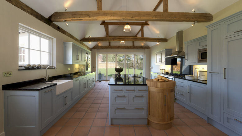 A huge gorgeous kitchen with periwinkle cabinets and large wooden ceiling beams