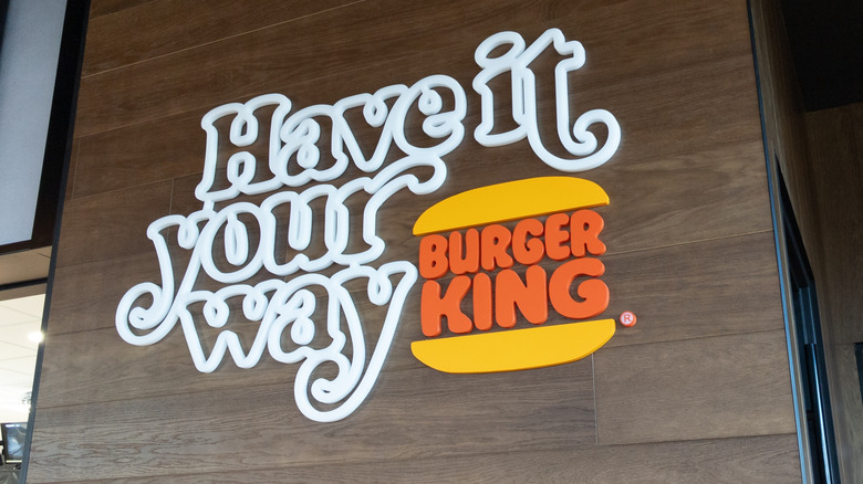A sign on the wall of a Burger King restaurant that reads "have it your way" next to the burger king logo