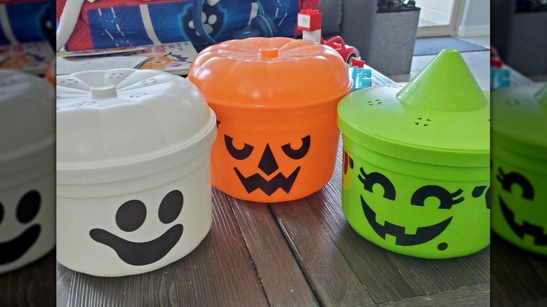 three McDonald's Halloween Boo Buckets in white, orange, and green on a table in front of other toys
