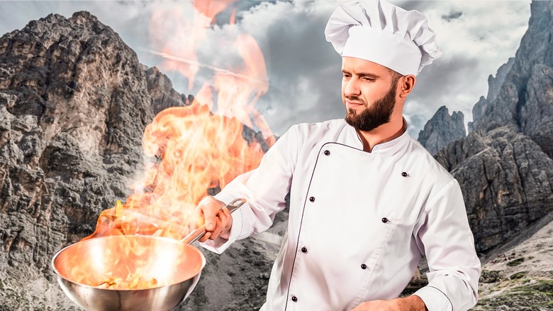 man cooking in mountain scene