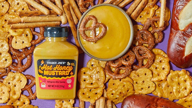 Trader Joe's Hot Honey Mustard bottle surrounded by pretzels with a bowl of mustard and a pretzel on top