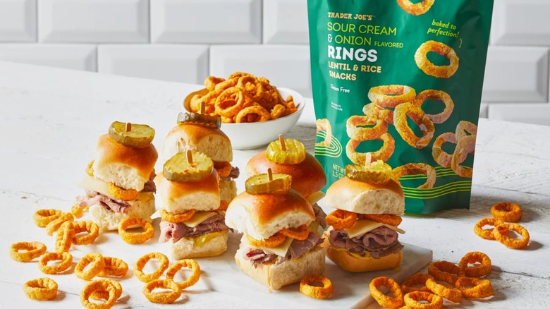 A bag of Trader Joe's Sour Cream & Onion Flavored Rings next to sliders with rings inside