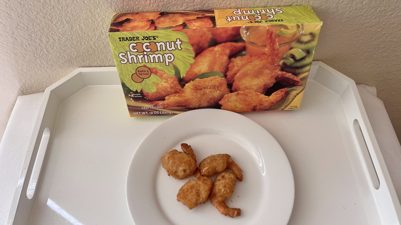 Trader Joe's coconut shrimp baked and served on a plate with the whole box of frozen shrimp in the back