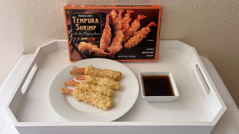 Trader Joe's cooked Tempura shrimp on a plate with the box in the back and soy sauce on the side