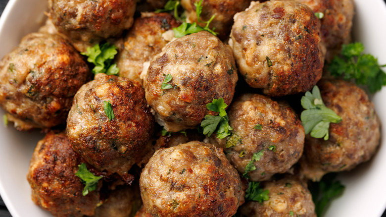 Closeup of a pile of freshly cooked meatballs garnished with freshly chopped herbs