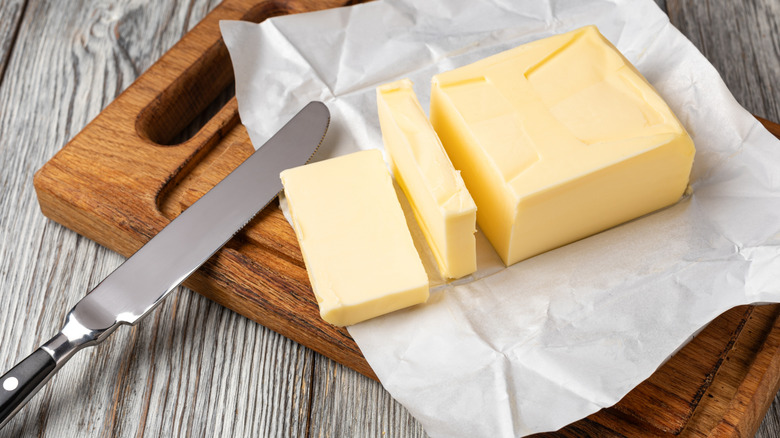 Fresh butter sliced on a cutting board with a knife on the side