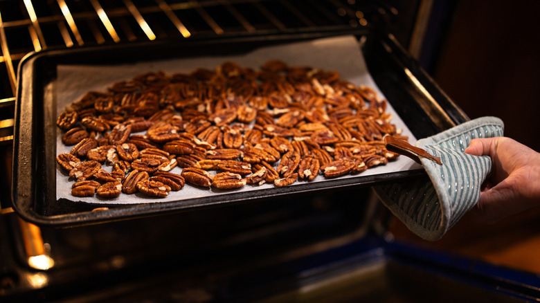 Person pulling out roasted pecans out of the oven
