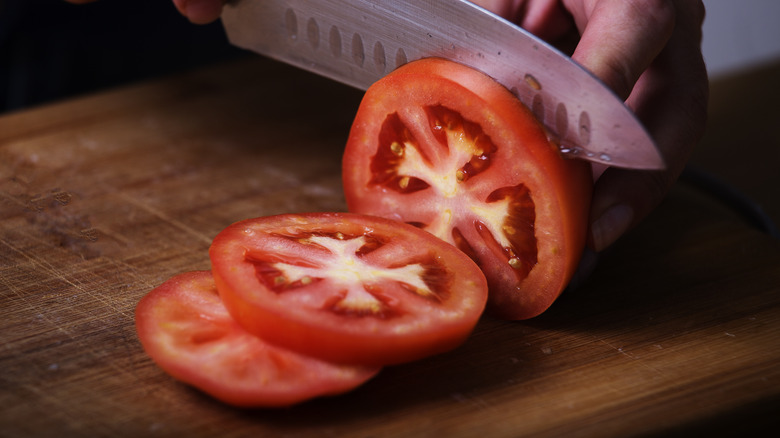 slicing tomato on a cutting board