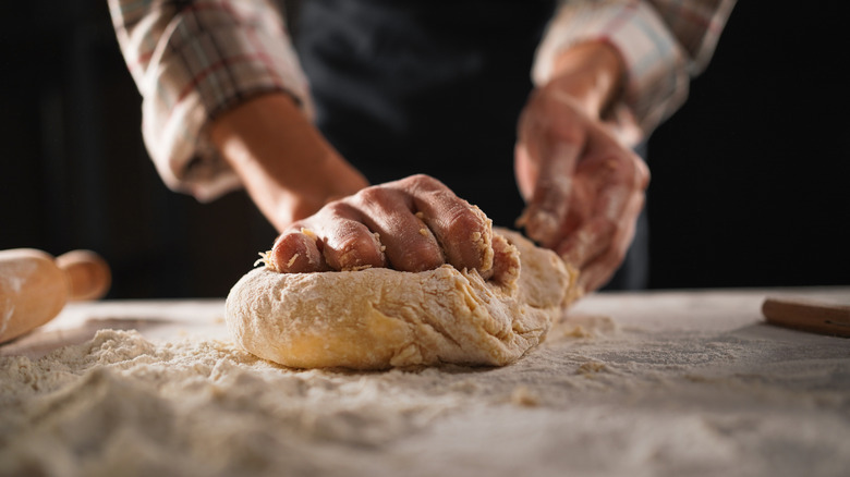 Hands kneading bread dough on table