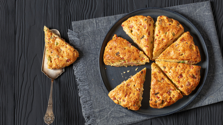 Plate of cheese and ham scones with one on metal cake server