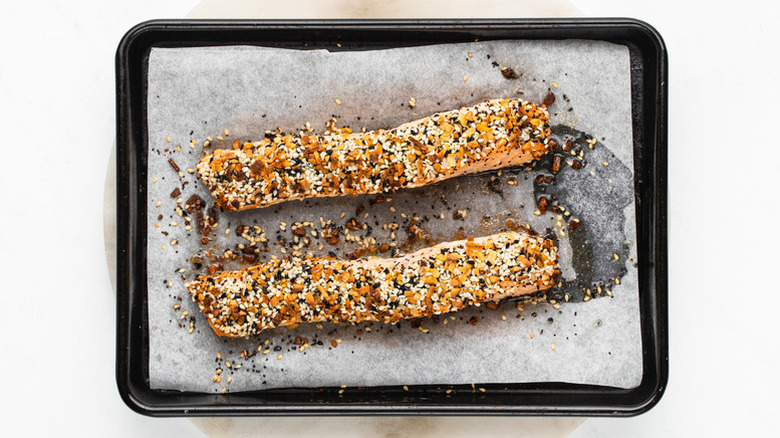 Two salmon fillets on baking sheet, topped with everything bagel seasoning