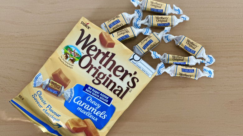 Open bag of Werther's No Sugar Added Chewy Caramels with scattered wrapped candies on wooden table