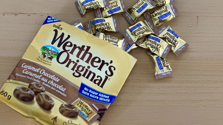 Open bag of Werther's Sugar Free Caramel Chocolate Hard Candies with scattered wrapped candies on wooden table