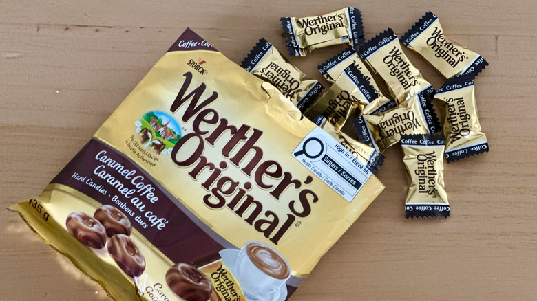 Open bag of Werther's Coffee Caramel Hard Candies with scattered wrapped candies on wooden table
