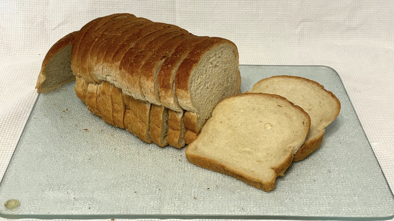 Whole Foods country white loaf sliced on cutting board and white background