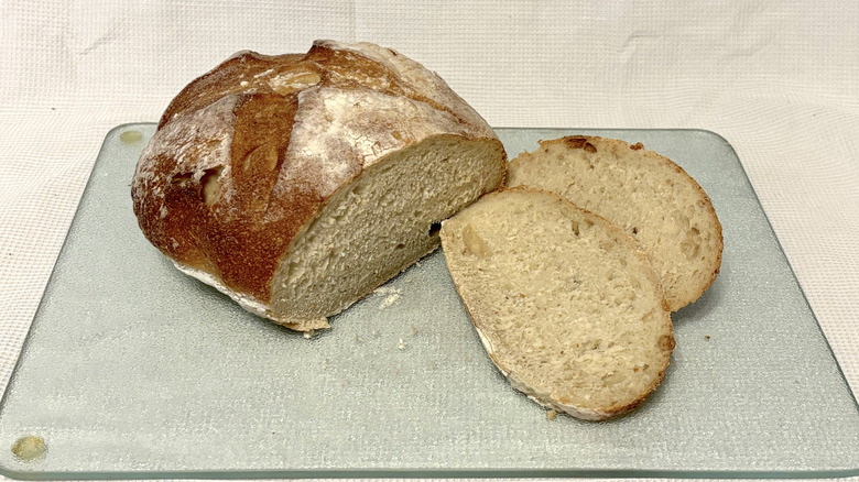 Whole Foods San Francisco sourdough partially sliced on cutting board and white background