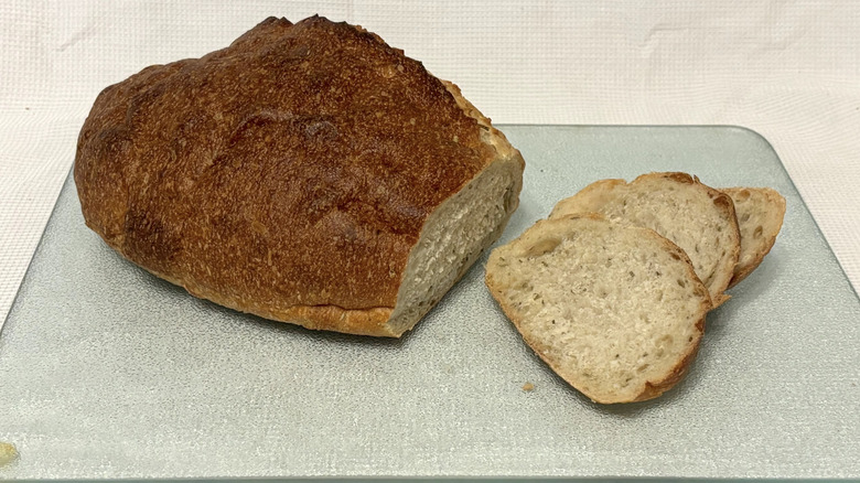 Whole Foods rosemary sourdough partially sliced on cutting board and white background
