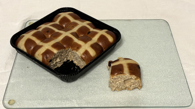 Whole Foods hot cross buns partially sliced on cutting board and white background