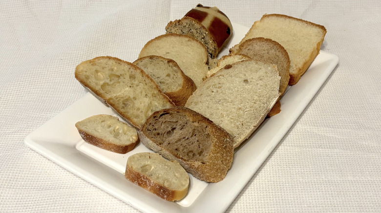 A variety of fresh bakery bread from Whole Foods, sliced, and on a white platter and background