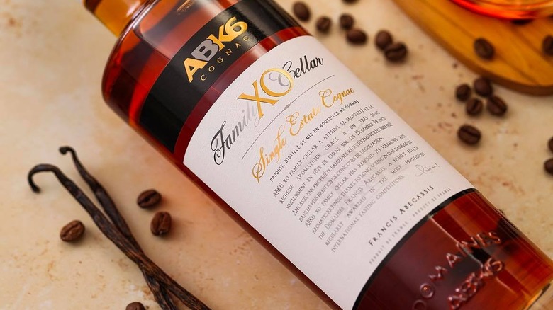 A bottle of ABK6 XO Family Cellar laid on its side surrounded by coffee beans and vanilla pods